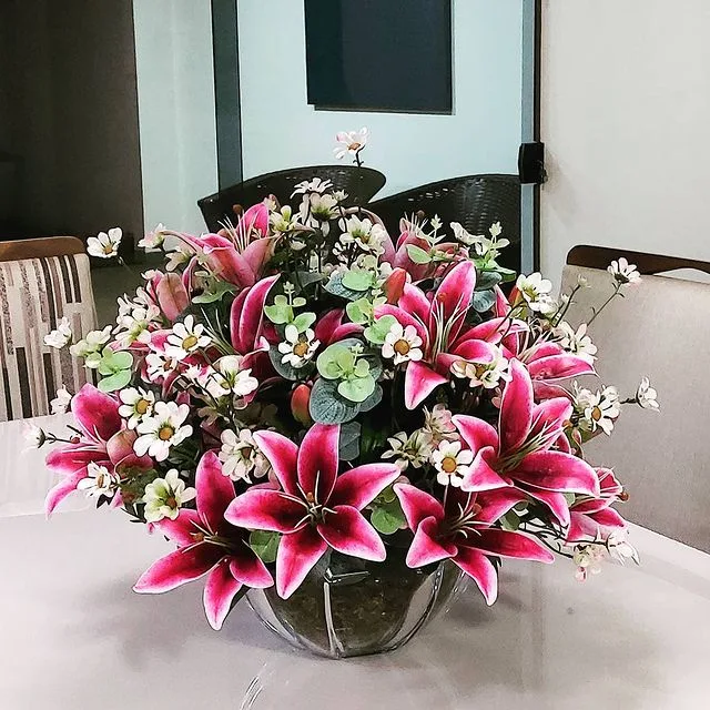 Arranjo de lírios rosa em vaso de vidro sobre a mesa