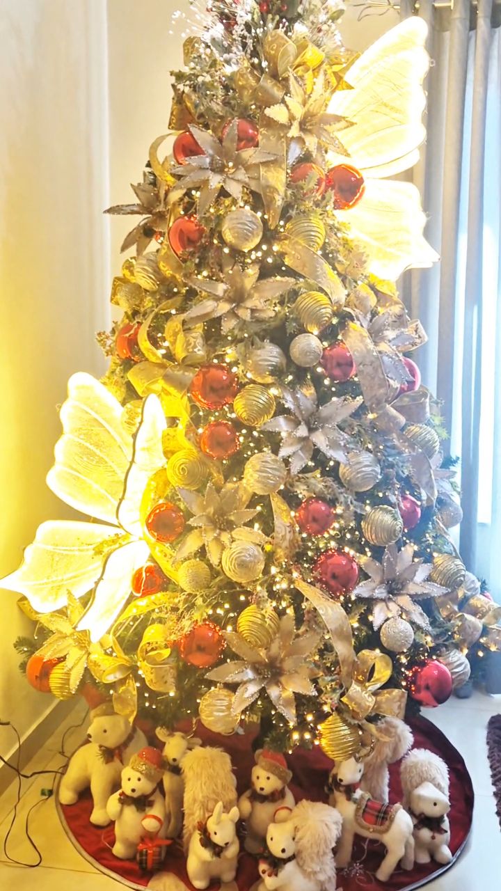 Árvore de Natal grandiosa em dourado e vermelho com flores iluminadas