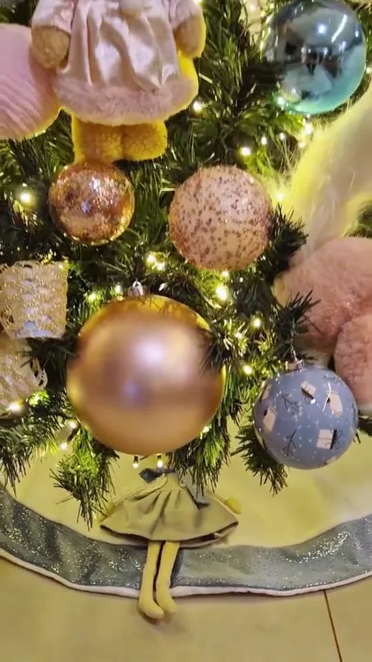 Detalhe de bolas de Natal douradas e rosê em meio às luzes